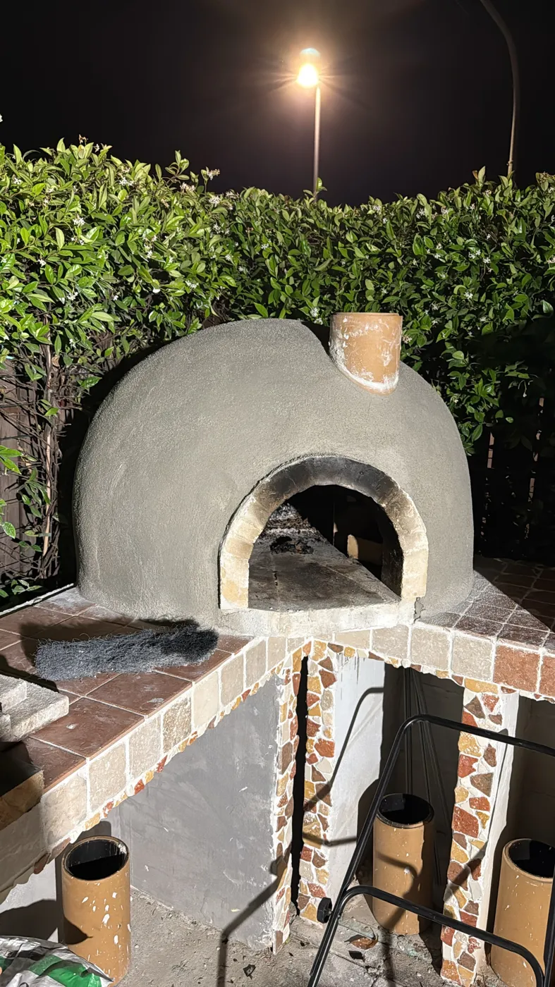 Forno per pizza intonacato con mosaico in pietra naturale, di notte